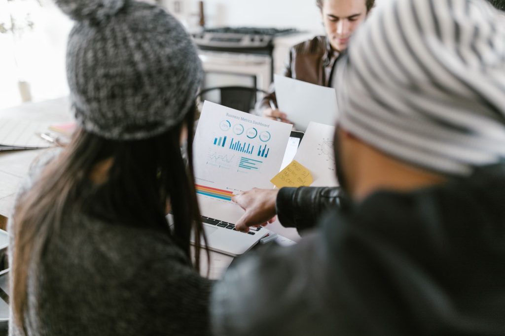 Team members discussing business metrics using printed charts in a cozy meeting space.